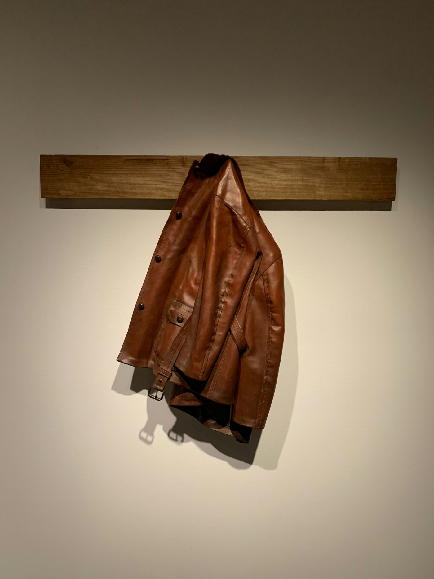 Brown leather jacket hanging on a wooden hook